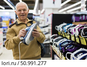 senor man pensioner buying iron in showroom of electrical appliance store. Стоковое фото, фотограф Татьяна Яцевич / Фотобанк Лори