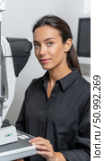 Optometrist performing eye exam using phoropter in ophthalmology clinic. Стоковое фото, фотограф Юрий Поздников / Фотобанк Лори