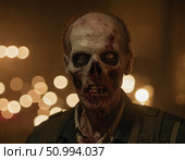A chilling zombie man with decayed skin and hollow eyes stares eerily at the viewer. Dim lights in the background create an unsettling atmosphere, enhancing his terrifying presence Generative AI. Стоковое AI-изображение, AI-художник Юлия Петровская / Фотобанк Лори
