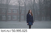Solitary student walking empty schoolyard during misty winter morning, embodying introspective calm amid silent, frost covered surroundings. Стоковое AI-видео, аниматор Данил Руденко / Фотобанк Лори
