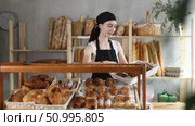 Young woman seller puts croissants in showcase. Стоковое видео, видеограф Яков Филимонов / Фотобанк Лори