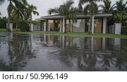 Reflecting puddles mirroring minimalist white villa, palm trees, green lawn after tropical rainfall in Thailand landscape. Стоковое AI-видео, аниматор Данил Руденко / Фотобанк Лори