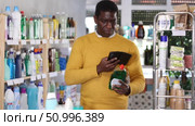 African man buyer scan QR code on packaging of dishwashing soap in shop. Стоковое видео, видеограф Яков Филимонов / Фотобанк Лори