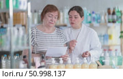 Woman choosing prescription medications with help of pharmacist. Стоковое видео, видеограф Яков Филимонов / Фотобанк Лори