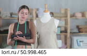 Female fashion designer drawing clothing on tablet in studio. Стоковое видео, видеограф Яков Филимонов / Фотобанк Лори