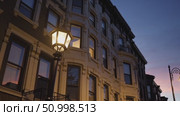 Soft evening illumination highlighting brownstone windows, street lamps glowing on quiet Brooklyn neighborhood sidewalks, capturing peaceful urban residential twilight scene. Стоковое AI-видео, аниматор Данил Руденко / Фотобанк Лори