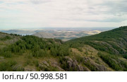 Scenic landscape featuring steep mountains and dense forests in a valley, with dramatic cloud formations above, highlighting the tranquility of the natural environment. Стоковое видео, видеограф Ирина Ручушкина / Фотобанк Лори