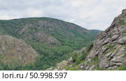 Scenic landscape featuring steep mountains and dense forests in a valley, with dramatic cloud formations above, highlighting the tranquility of the natural environment. Стоковое видео, видеограф Ирина Ручушкина / Фотобанк Лори