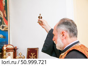 Russia, Rostov-on-Don - May 30, 2014: An Armenian priest holds a bird figurine in his hand and performs the rite of baptism over the font. Редакционное фото, фотограф Екатерина Красникова / Фотобанк Лори