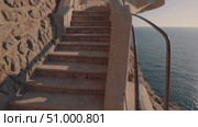 Steep stone stairway winding down rocky Mediterranean coastline, golden sunset light illuminating weathered steps leading toward tranquil azure waters. Стоковое AI-видео, аниматор Данил Руденко / Фотобанк Лори