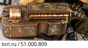 Close-up of an ornate hurdy-gurdy featuring detailed dragon engravings. Antique musical instrument with engraved mythical scenes and vibrant accents. Стоковое фото, фотограф Алла Чесноковва / Фотобанк Лори