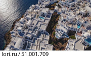 Whitewashed architecture cascading down volcanic cliffs of Santorini, revealing pristine hotels, swimming pools, and breathtaking views across sparkling Aegean waters. Стоковое AI-видео, аниматор Данил Руденко / Фотобанк Лори