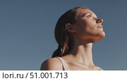 Woman tilting head back, eyes closed, absorbing warm sunlight against blue sky backdrop, radiating serene relaxation and inner calm. Стоковое AI-видео, аниматор Данил Руденко / Фотобанк Лори