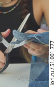 A young girl is creating gloves from old jeans. She cuts them into the shape of her palms with scissors. Стоковое видео, видеограф Strunov David / Фотобанк Лори