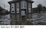 Concerned male standing amid floodwaters near church building, expressing emotional aftermath of devastating natural disaster with powerful visual narrative. Стоковое AI-видео, аниматор Данил Руденко / Фотобанк Лори