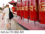 A tourist turns prayer drums of khurul, Buddhist temple Golden Abode of Buddha Shakyamuni, largest Buddhist temple in Europe, Elista, Kalmykia, Russia, July, 4, 2025. Редакционное фото, фотограф Екатерина Топорова / Фотобанк Лори