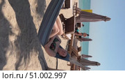 A 50-year-old woman on the beach in Doha is riding a hammock. Стоковое видео, видеограф IRYNA ZAKHARANKA / Фотобанк Лори
