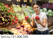Woman near vegetable stand in store choose radish. Стоковое фото, фотограф Яков Филимонов / Фотобанк Лори