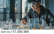 A professional examines intricate architectural models using advanced mixed reality technology amid a bustling city backdrop. Стоковое AI-видео, аниматор Данила Большаков / Фотобанк Лори