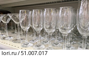 Rows of clear glass champagne flutes and martini glasses on a store shelf. Perfect for concepts related to glassware, celebrations and barware. Стоковое фото, фотограф Елена Никишина / Фотобанк Лори