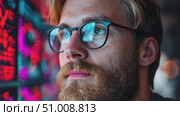 A man with glasses intensely studies screen displays filled with data, surrounded by urban ambiance in the evening. Стоковое AI-видео, аниматор Данила Большаков / Фотобанк Лори