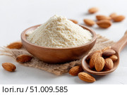 Almond flour. Almond nuts and almond flour in a wooden bowl and spoon. White table background. Grated almonds pile. Gluten-free produce for health. Low Carb Keto, celiac, paleo, and wheat-free diets. Стоковое AI-изображение, AI-художник Марина Демидюк / Фотобанк Лори