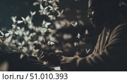 Creative writer connects with inspiration as butterflies surround him in a cozy environment at night. Стоковое AI-видео, аниматор Сергей Толмачёв / Фотобанк Лори