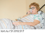 An elderly woman suffers from the flu and runny nose. The pensioner blows her nose in the nasal raft. Стоковое фото, фотограф Михаил Решетников / Фотобанк Лори