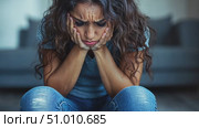 A woman expresses deep emotions while sitting on the floor in her living room, appearing overwhelmed and in deep thought during the evening. Стоковое AI-видео, аниматор Данила Большаков / Фотобанк Лори