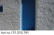 Discover a picturesque whitewashed house with a blue door situated by the coast, surrounded by a tranquil landscape and vibrant blue sky. Стоковое AI-видео, аниматор Данила Большаков / Фотобанк Лори
