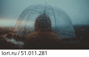 Person stands under a transparent umbrella in the rain by a scenic waterfront during cloudy weather at dusk. Стоковое AI-видео, аниматор Сергей Толмачёв / Фотобанк Лори