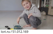 Child mixing paint in a bowl on the floor. Стоковое видео, видеограф Константин Шишкин / Фотобанк Лори