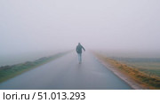 Person walks alone on a foggy road in a serene landscape surrounded by nature at dawn. Стоковое AI-видео, аниматор Сергей Толмачёв / Фотобанк Лори