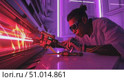 In a sleek lab illuminated by neon lights, a scientist carefully manages a laser device during an innovative experiment. Стоковое AI-видео, аниматор Данила Большаков / Фотобанк Лори
