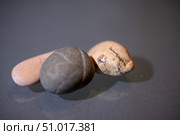 Minimalistic close up of three polished stones in earthy tones resting on a smooth grey surface. Стоковое фото, фотограф Виктор Ветошкин / Фотобанк Лори