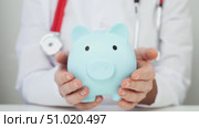 A Doctor Woman Holding a Piggy Bank in Her Hands. Concept of additional medical insurance. Lca. Стоковое видео, видеограф Igor Skripachev / Фотобанк Лори