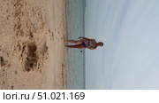 A 50-year-old European woman in a swimsuit walks along the beach in Doha, Qatar. Стоковое видео, видеограф IRYNA ZAKHARANKA / Фотобанк Лори