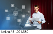 Young man using a multifunction printer in an office setting while reviewing printed documents and accessing digital features. Стоковое фото, фотограф Сергей Толмачёв / Фотобанк Лори