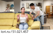 Pleased young couple choosing convenient sofa in large furniture shop. Стоковое видео, видеограф Яков Филимонов / Фотобанк Лори