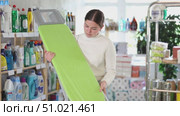 Girl housewife in household store examines goods, chooses ironing board. Стоковое видео, видеограф Яков Филимонов / Фотобанк Лори