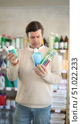 Thoughtful male shopper carefully selecting toothbrush and toothpaste, checking dental care product details while helpful female store assistant offering bottle of mouthwash. Стоковое видео, видеограф Яков Филимонов / Фотобанк Лори