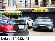 A black car is parked next to a white car near the Rasputin restaurant. Belarus. Minsk. 05.08.25. Редакционное фото, фотограф Ярославский Максим / Фотобанк Лори