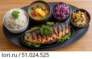 Enjoying a traditional Japanese longevity meal with grilled fish and sides. Стоковое AI-изображение, AI-художник Katsiaryna Repich / Фотобанк Лори