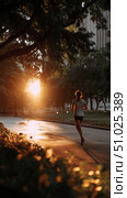 Morning runner enjoys the tranquility of a park at sunrise with golden light filtering through trees. Стоковое AI-изображение, AI-художник Сергей Толмачёв / Фотобанк Лори
