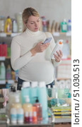 Mindful pregnant shopper scanning barcode on bottle of sun lotion with phone, carefully checking for eco-friendly and baby-safe ingredients, choosing best option. Стоковое видео, видеограф Яков Филимонов / Фотобанк Лори