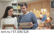 European married couple considering wood samples for apartment decoration and renovation, they choose laminate flooring. Buyers in a furniture salon discuss the quality of wooden materials. Стоковое видео, видеограф Яков Филимонов / Фотобанк Лори