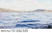 Lake Bannoe, Russian Federation - July 31, 2025: Serene lake view with gentle ripples reflecting clouds and distant hills under a bright blue sky, showcasing natural beauty and tranquility. Редакционное видео, видеограф Ирина Ручушкина / Фотобанк Лори