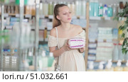 Attentive pregnant woman holding feminine pads trying to make choice in drugstore. Стоковое видео, видеограф Яков Филимонов / Фотобанк Лори
