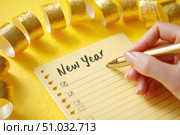 Woman's hand writing in empty notebook at the desk with Christmas decoration. Back to life, goal list. Plan, goals, checklist, idea concept. Top view, copy space. New Year. Blank White Paper Sheet. Стоковое AI-изображение, AI-художник Марина Демидюк / Фотобанк Лори