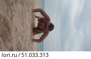 A 50-year-old European woman in a swimsuit and pareo is doing push-ups on the sand at a beach in Doha. Стоковое видео, видеограф IRYNA ZAKHARANKA / Фотобанк Лори